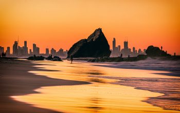 The sunset view of the Currumbin Beach in the twilight and the urban skyline of  Gold Coast in the dusk