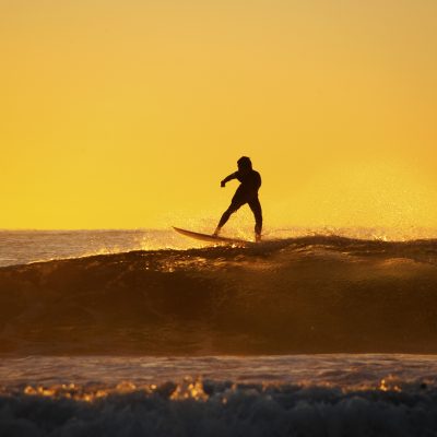 Young surfer standing on the wave